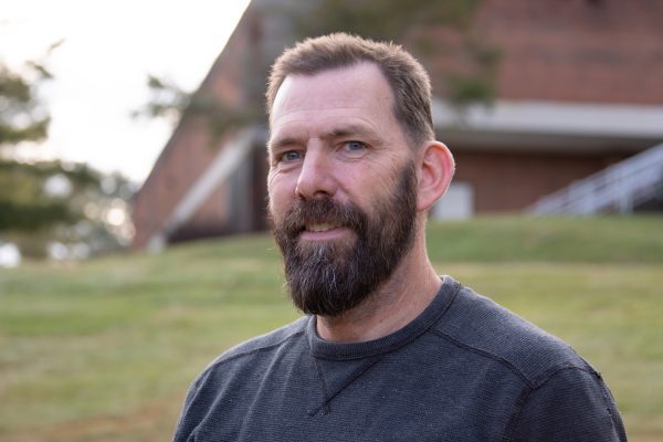 An image of Steve Miller standing in front of a grassy knoll on the Concord Campus.