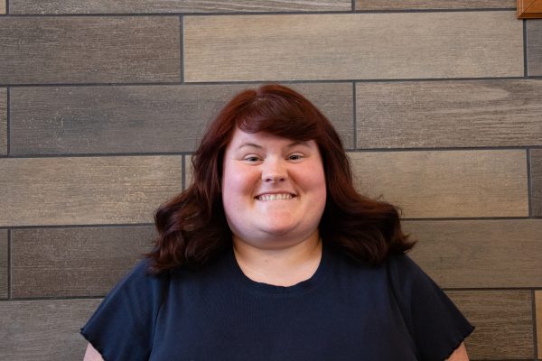 A photo of Brianna Lipscomb standing in front of a slate tile wall.