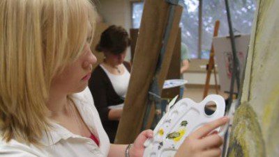 A Concord University studio art student painting in a classroom located in the Alexander Fine Arts Center