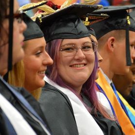 A group of graduates sitting together and smiling during the commencement ceremony