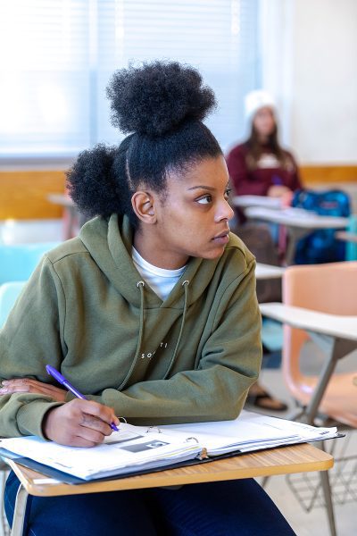 A student writing in a notebook inside of a classroom at Concord University