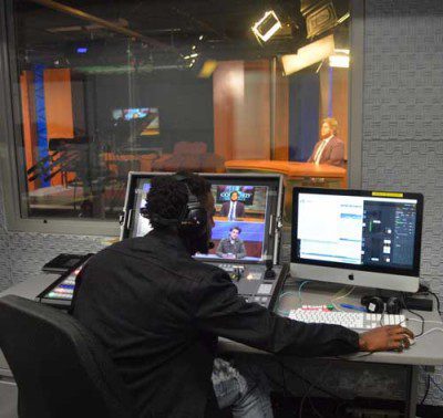 A student working on the audio and visuals for a student news broadcast