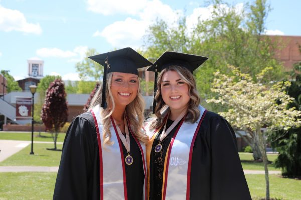Two CU RISE graduates wearing their caps, gowns, and CU RISE stoles