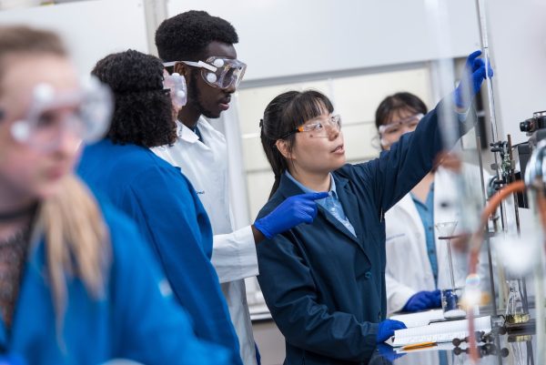 Dr. Yin Hong working with students in a chemistry lab on campus