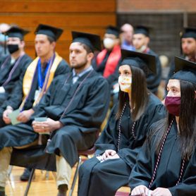 Graduates wearing their caps and gowns and sitting at the commencement ceremony