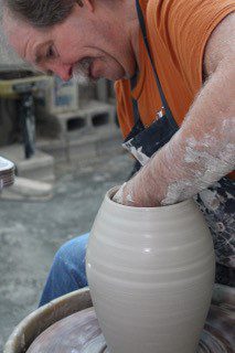 Josh Deweese throwing a clay pot on a pottery wheel