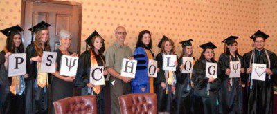 Psychology graduates posing for a group photo with the faculty holding letters that spell psychology
