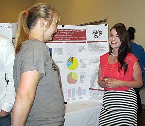 Lori Conner next to her poster about her research titled Females Breaking Barriers: Women Entering Law Enforcement and Breaking Down The Gender Barrier