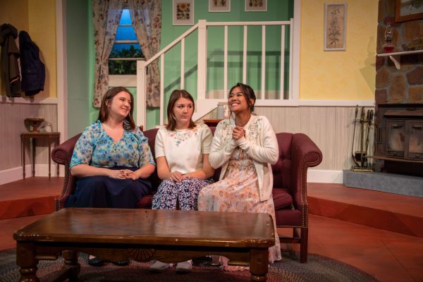 IMG_8608_Edited (1) Three Concord students sitting on a couch on the set of A Bad Year For Tomatoes. The three ladies are wearing bright floral clothes