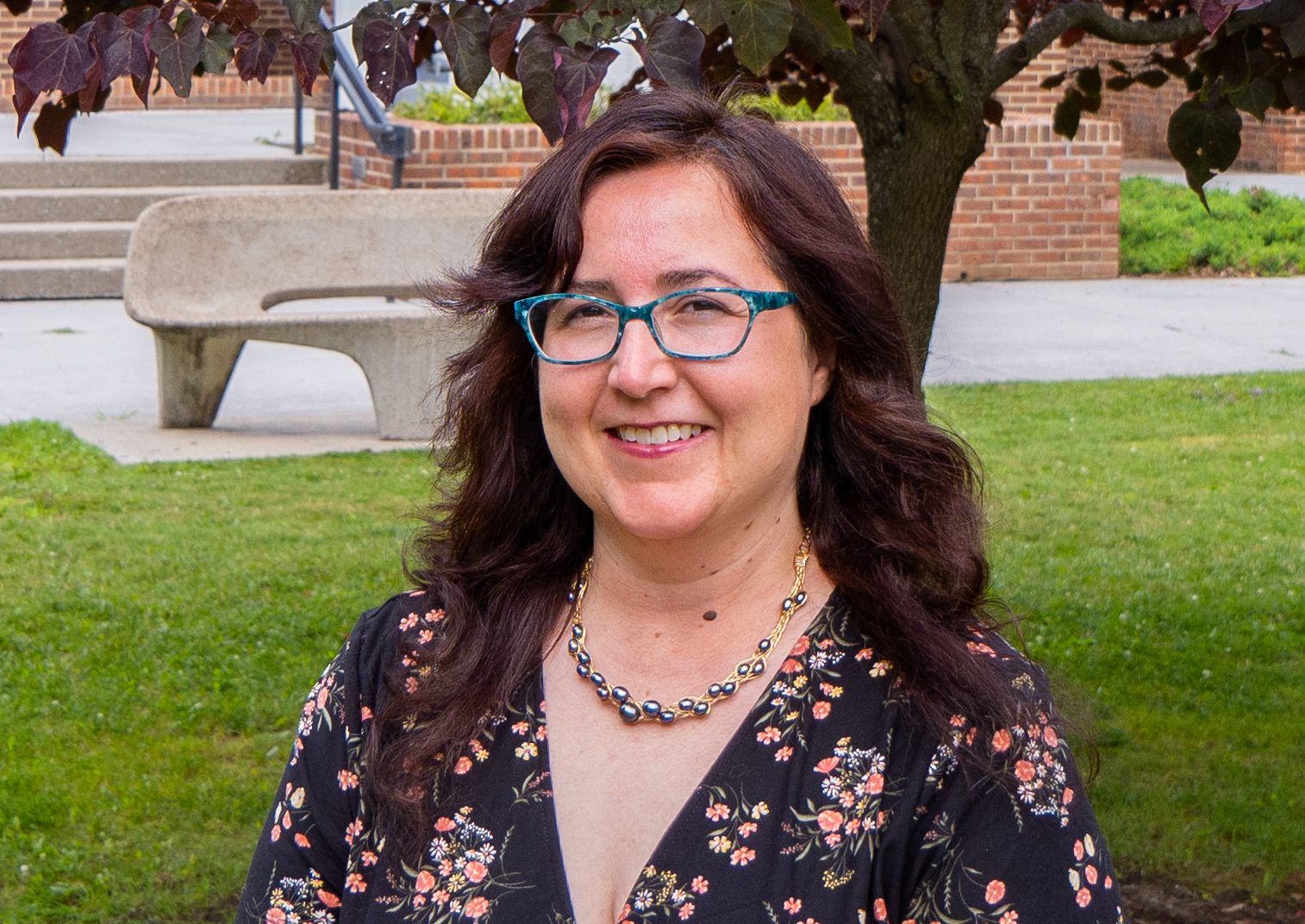 A photo of Assistant Professor of Graphic Design, Beth Little. Beth is pictured outside, in front of the Alexander Fine Arts Building.