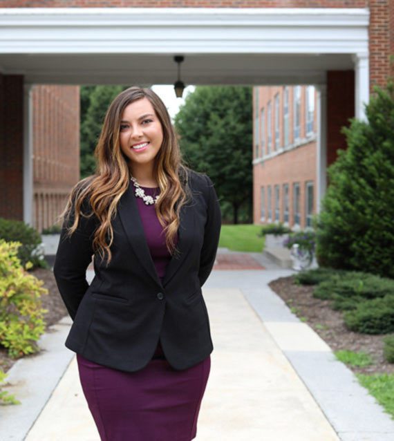 A photo of Concord University alumni Jade Gravley between the J. Franklin Marsh Library and the Marsh Hall Administration Building