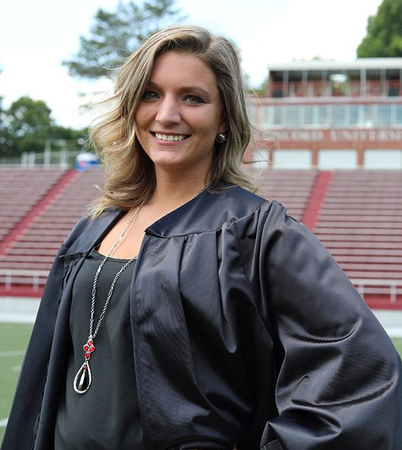 A photo of Mikayla McMullen in front of the football field bleachers
