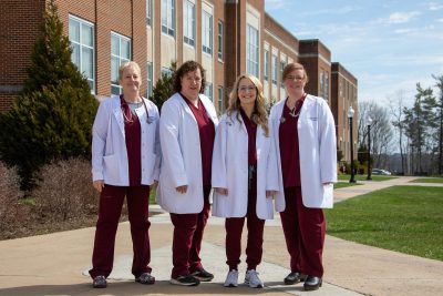 Department of Nursing Faculty stand together in front of Marsh Hall on Concord University's main campus. Faculty members include (from left to right) Professor Danita Farley, Dr. Martha Snider, Professor Amanda Nichols, and Dr. Michele Holt.