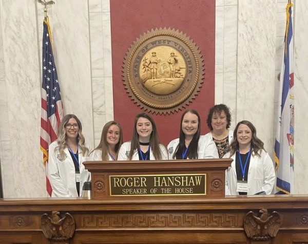 Group of BSN students pose behind the podium of Roger Hanshaw, West Virginia's Speaker of the House.