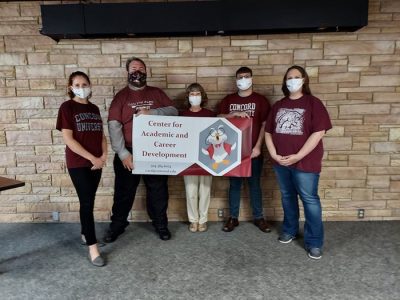 The CACD Staff posing with their banner on the stage at Subway Sides