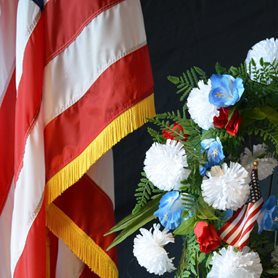 An American flag next to a bouquet of red, white, and blue flowers