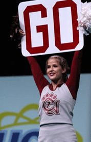 A Concord University cheerleader holding a sign that says Go